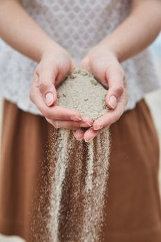 Girl pouring sand out of her hands. Close-up