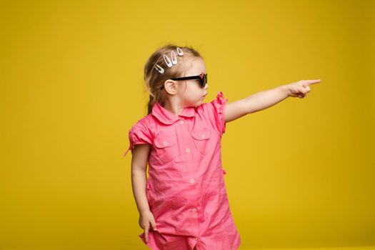 Little girl in dress and sunglasses indicating the direction.