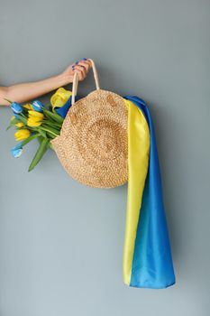 Ukrainian girl in a blue dress holds in a bag yellow and blue tulips