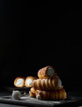 baked tubules filled with whipped egg whites cream on a black wooden kitchen board