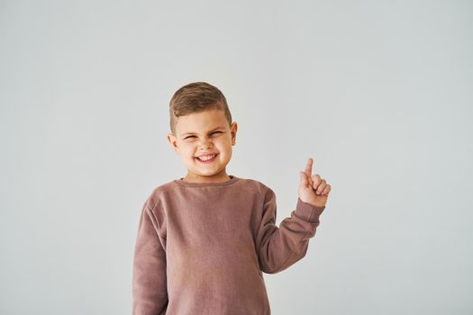 Happy handsome child boy smiling and pointing finger right side. Business advertising for children stores and shops.
