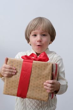Surprised child holding Christmas gift box in hand. Boy on white background. New year and x-mas concept.