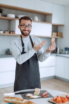 attractive man showing a piece of delicious cheese