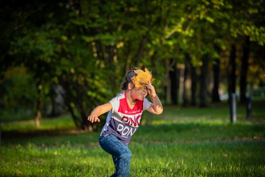 Girl laughs and plays with leaves in the park in summer. Russia Moscow September 24, 2020