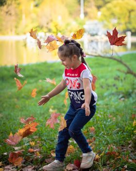 The girl throws colorful maple leaves for a walk in the park. Russia Moscow September 24, 2020