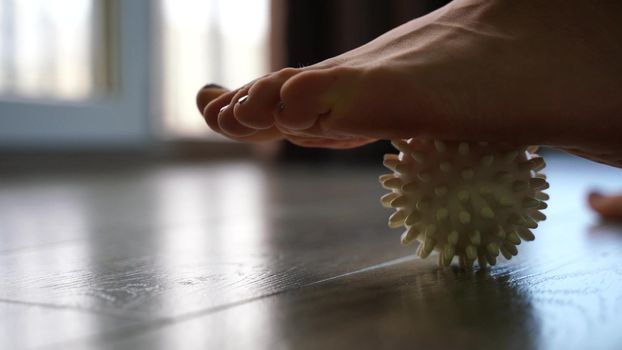 Close-up, a woman doing a foot massage with a special massage ball. The concept of prevention and treatment of flat feet.