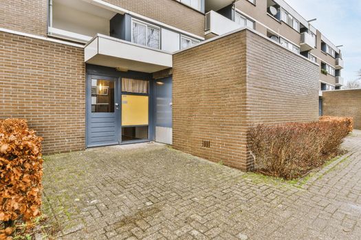 Entrance to a cozy brick residential building with a tiled walkway