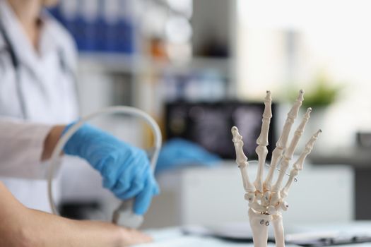 Doctor do ultrasound of hand, skeleton hand model on desk, medical anatomy science