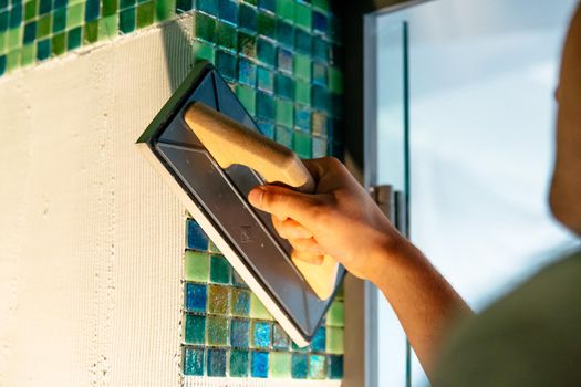 Worker applying mosaic tiles, bath renovation
