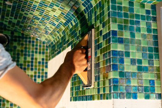 Worker applying mosaic tiles, renovation concept