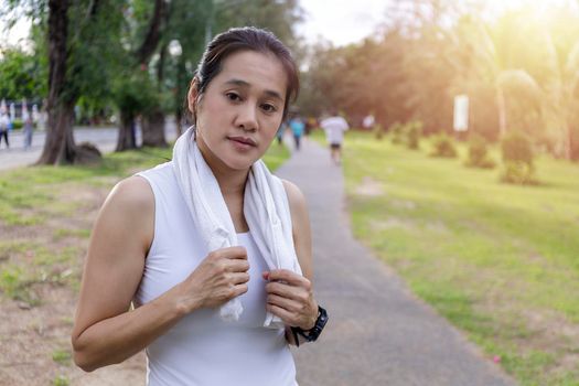 Portrait attractive smiling fit woman with white towel resting after workout sport exercises outdoors on a background of park trees.  Women relax after running, Healthy lifestyle well being wellness happiness concept.