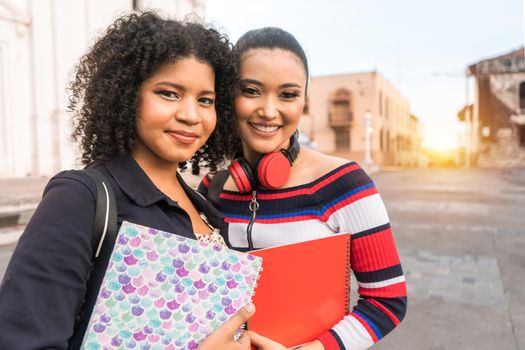 Two multiracial Latina students looking at the camera and smiling in the central park of Leon Nicaragua