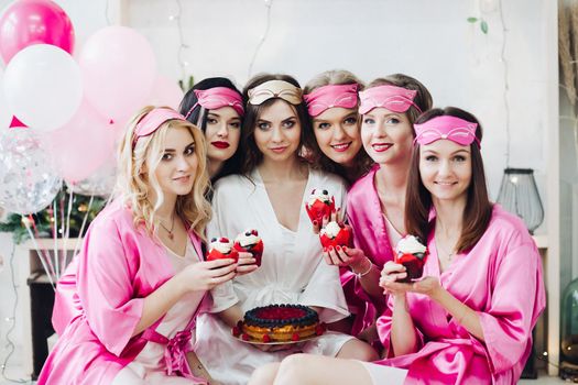 Pretty girls in pink robes and sleep masks with desserts at bridal showers.