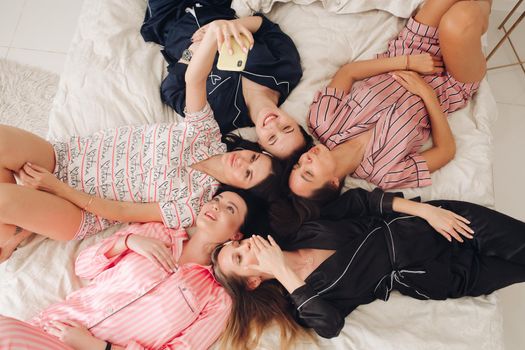 Pretty girls in pyjamas taking selfie on bed.