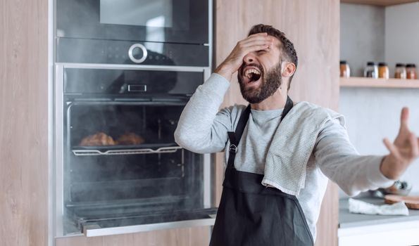 surprised man standing near the oven with burnt croissants.