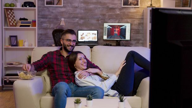 Charming couple lying on the couch watching a movie
