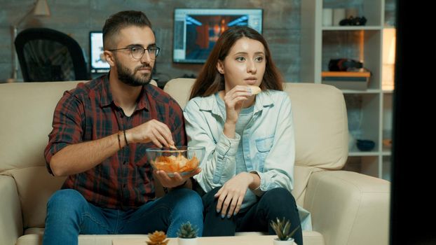 Concentrated caucasian young couple while watching tv