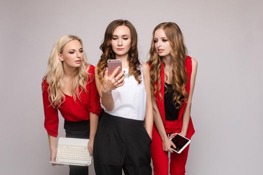 Stylish elegant woman in red suit using tablet with friends.