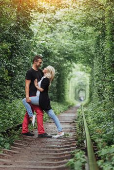 Loving couple in a tunnel of green trees on railroad