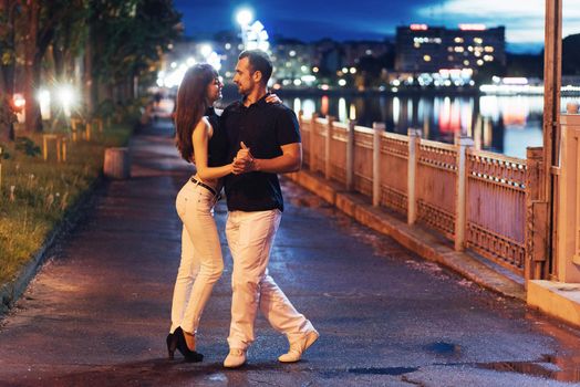 young couple dancing tango on the embankment