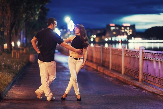 young couple dancing tango on the embankment