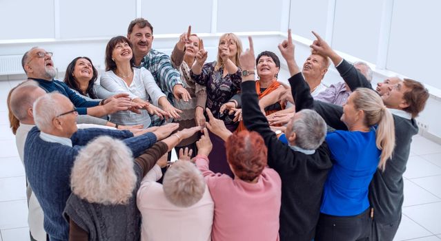 Cheerful senior people exercising with arms raised at retirement