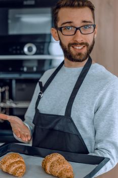 smiling man holding a tray of fresh croissants