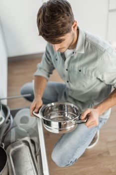 young man looking at clean dishes in dishwasher