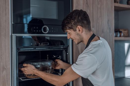 young man warming up dinner in the oven
