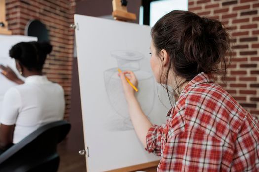 Painter woman drawing artistic vase on white canvas