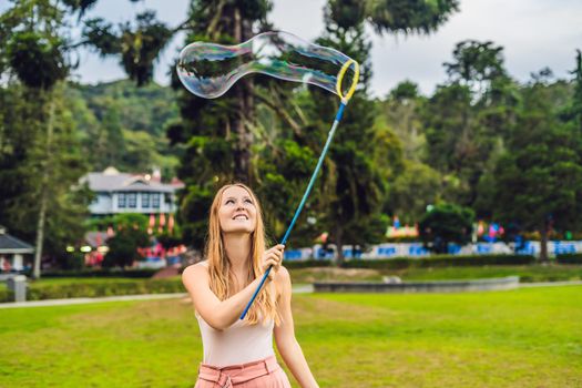Happy carefree young woman blowing soap bubbles