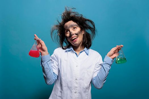 Crazy chemist acting dumb while having glassware beakers filled with liquid substances.
