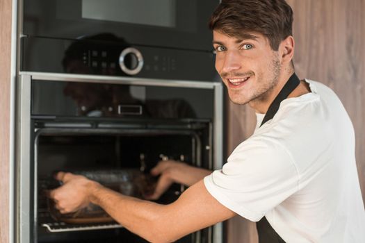 man opening the oven in the home kitchen