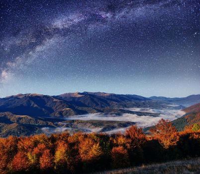 Fantastic starry sky and majestic mountains in the mist. Dramati