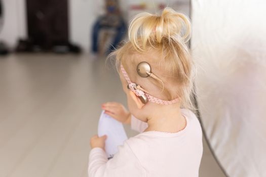 Cochlear implant for baby. Deaf child with hearing aid at home