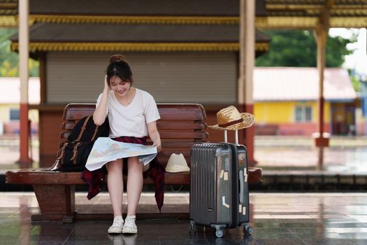 Pretty Young traveler woman looking on maps planning trip at train station. Summer and travel lifestyle concept.