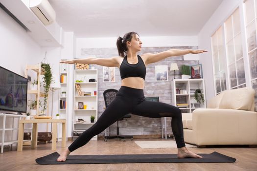 Attractive caucasian woman doing virabhadrasana yoga pose.