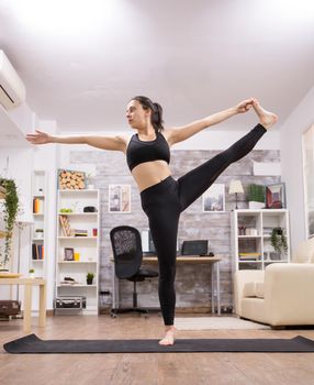 Caucasian young woman doing a beautiful yoga pose in living room.
