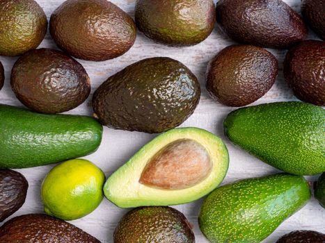 Mix of ripped and green avocados on white wooden board