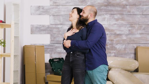 Happy young couple hugging each other in their new apartment