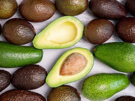 Mix of ripped and green avocados on white wooden board