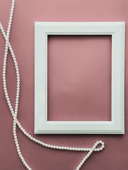 Vertical frame and pearl jewellery on blush pink background as flatlay design, artwork print or photo album