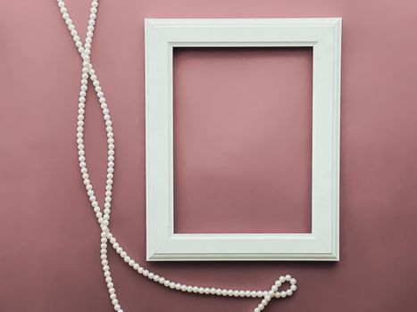 Vertical frame and pearl jewellery on blush pink background as flatlay design, artwork print or photo album