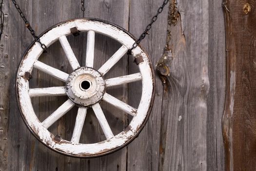 An old wooden carriage wheel hanging on the barn wall