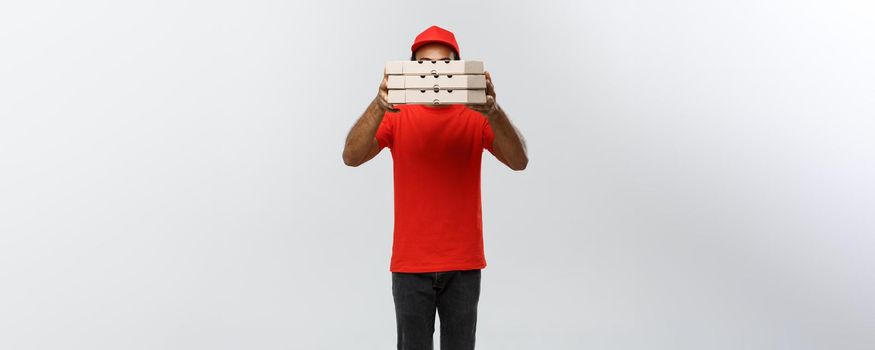 Delivery Concept - Portrait of Handsome African American Pizza delivery man hiding behide Pizza boxes. Isolated on Grey studio Background. Copy Space.