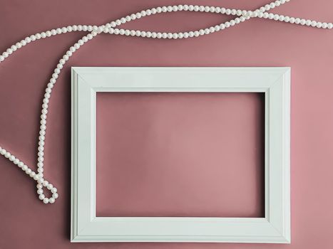 Horizontal art frame and pearl jewellery on blush pink background as flatlay design, artwork print or photo album