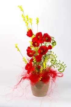 Composition with artificial flowers in a pot on white background. Ekibana from red artificial pions.