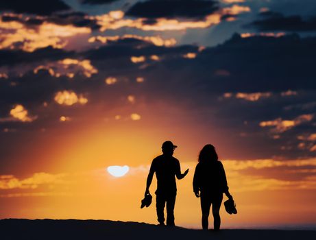 Couple at sunset beach in Santa Monica, California, United States of America. Sun and clouds in background.