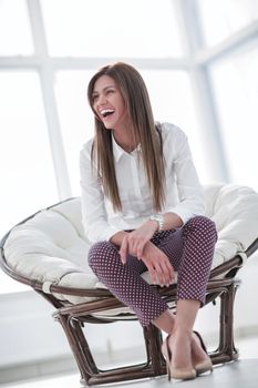 laughing young woman sitting in comfortable chair