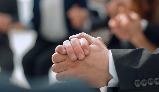 Business group in a circle holding hands indoors